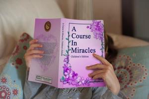 collection of three A Course in Miracles, children's edition books stacked on desk